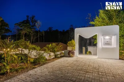 a white building with a sign on it at night at StayVista at Mudra Tattva - Pvt Pool,Lawn,Jacuzzi 2BR Luxury Rooms in Suntikoppa