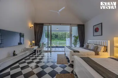 a bedroom with a bed and a tv and a bathroom at StayVista at Mudra Tattva - Pvt Pool,Lawn,Jacuzzi 2BR Luxury Rooms in Suntikoppa