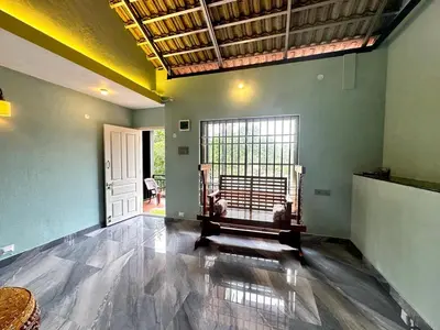 a living room with a large window and a couch at Leaf links Coorg in Siddapur