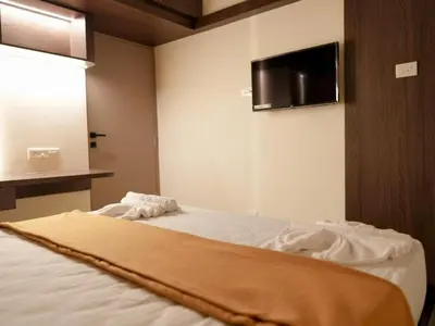 a bedroom with a bed with a tv on the wall at Amaira Studio living - Coimbatore in Coimbatore
