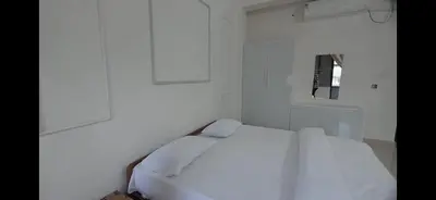 a white bed in a white room with a mirror at AZURE stay happy in Pudunagaram