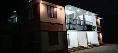a tall building with a balcony at night at Green palace service villa in Kalpetta