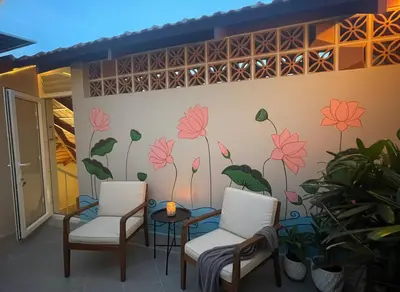 two chairs and a table with a flower mural on a wall at Nesara Home Stay Mysuru in Mysore