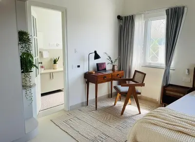 a bedroom with a desk and a bed and a window at Nesara Home Stay Mysuru in Mysore