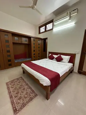 a bedroom with a large bed with red pillows at Villa Vinaya- Comfort, Calm & Charm in Mysore in Mysore