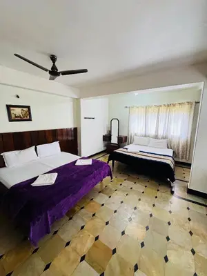 a large bedroom with two beds and a window at Hotel caveri comfort in Madikeri