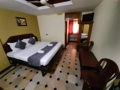 a bedroom with a bed and a chair in it at Hotel caveri comfort in Madikeri