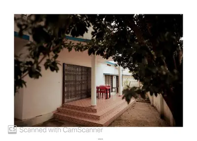 a building with two red chairs and a gate at Coorg River Song Homestay in Kushālnagar