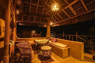 a porch with a couch and chairs and a chandelier at Earthen Pool Villa! Redefining Luxury! in Marayoor