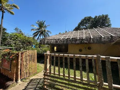a house with a thatch roof and a wooden fence at Earthen Pool Villa! Redefining Luxury! in Marayoor