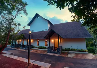 a white building with a black roof at Achutham Cottages Wayanad by VOYE HOMES in Padinjarathara