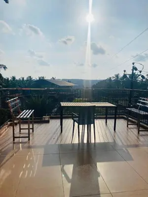 a table and two chairs on a deck with the sun at Neurogreen Apartments in Kottakkal