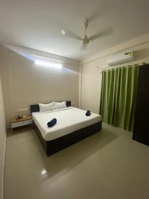 a bedroom with a bed and a green curtain at Neurogreen Apartments in Kottakkal