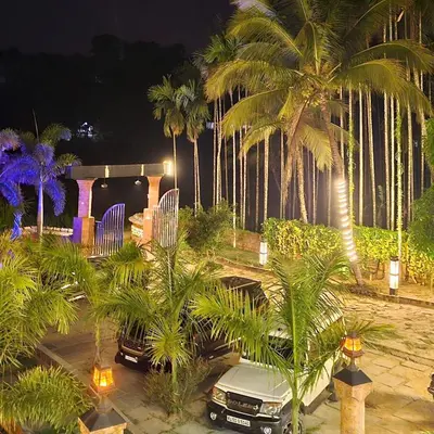 a car parked in front of a house with palm trees at Rendezvous Jungle Resort in Sultan Bathery