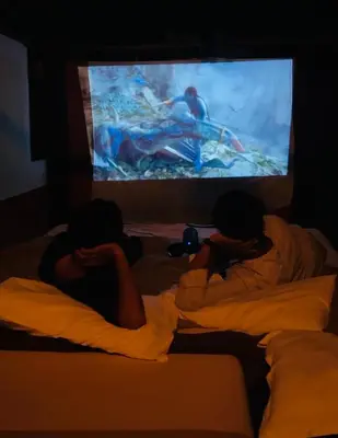 two people laying in bed in front of a tv at Kottaram Heritage in Pallipuram