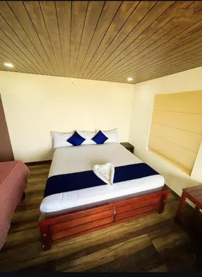 a bedroom with a bed with blue and white pillows at Bison valley resort Anikorai in Ooty