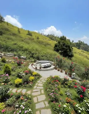 a garden with flowers and a fountain in the middle at Bison valley resort Anikorai in Ooty