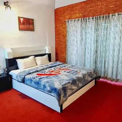 a bedroom with a large bed with a red carpet at Wings Cottage in Ooty