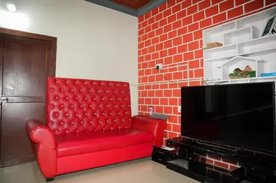 a red chair in a living room with a tv at Dua farms in Sultan Bathery
