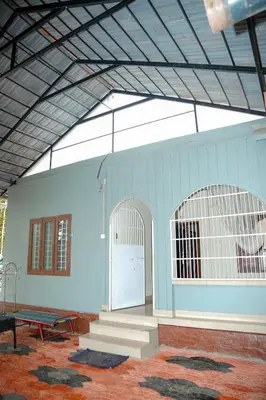 a blue building with a gate and a ping pong table at Dua farms in Sultan Bathery