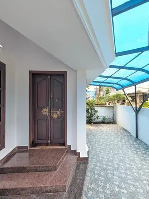 a entrance to a house with a wooden door at Sankeerthanam - Lounge in serenity in Ernakulam