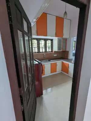 an open door to a kitchen with orange and white cabinets at Sankeerthanam - Lounge in serenity in Ernakulam