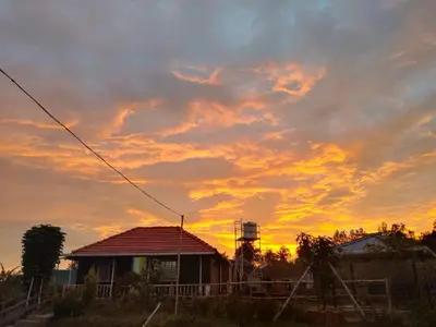 a sunset with a house in the foreground at Airin's Villa in Agali