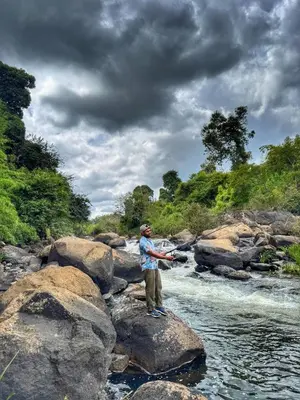 a man standing on some rocks in a river at Rafters Retreat Coorg - The Riverside Homestay in Srimangala