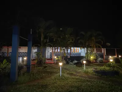 a building with lights in the yard at night at Rafters Retreat Coorg - The Riverside Homestay in Srimangala