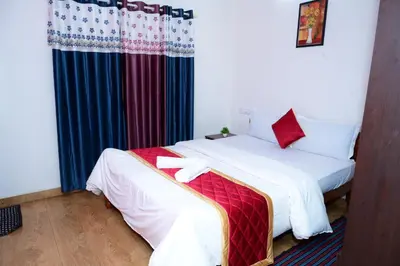 a bedroom with a bed with white sheets and red pillows at Coorg Holiday Homes in Madikeri