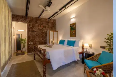a bedroom with a large bed with blue pillows at amã Stays & Trails - Highland Breeze , Coimbatore in Coimbatore