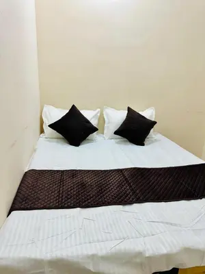 a bed with black and white pillows on it at Flats in city center, next to NEXUS MALL in Mysore