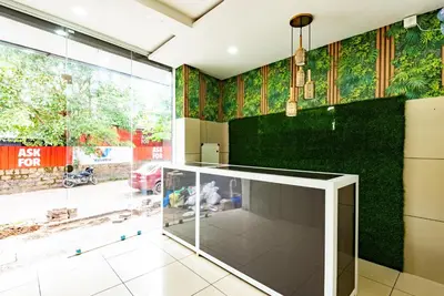 a glass elevator in a room with a green wall at Oxe residency in Kozhikode
