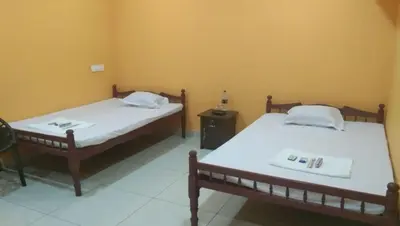 two twin beds in a room with a table at Charis Villa in Kunnamkulam near Guruvayoor in Kunnamkulam