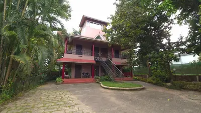 a pink house with a staircase in front of it at Rainbow Homestay Wayanad in Kalpetta