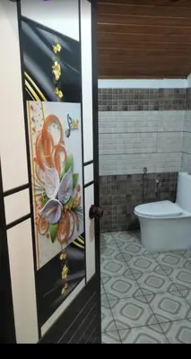 a bathroom with a toilet and a door with a painting at Morning mist holidays Thusharagiri in Vallikavungal