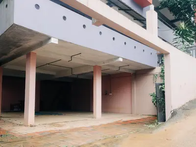 an empty parking garage with pink columns on a building at Fine Homes in Kalpetta