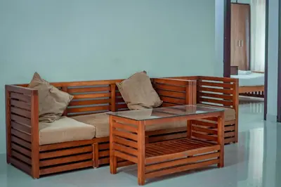 a wooden couch with a glass table in a room at Fine Homes in Kalpetta