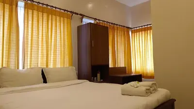 a bedroom with a large white bed with yellow curtains at LMS Palve Sugavasam in Ooty