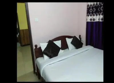 a white bed with black pillows in a room at LIMRA INN RESIDENCY cottage in Ooty