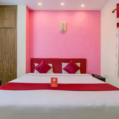 a bedroom with a large bed with a pink wall at LIMRA INN RESIDENCY cottage in Ooty