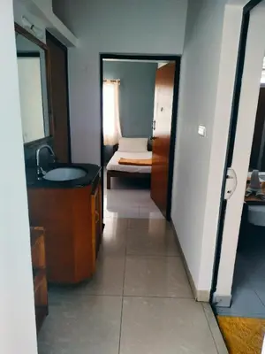 a bathroom with a sink and a bedroom with a bed at The Palmyrah Tenements in Mysore