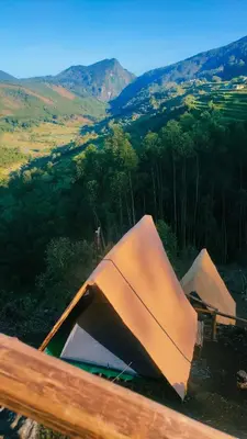 two tents in a field with mountains in the background at Daddy's MAD house in Kottakamboor
