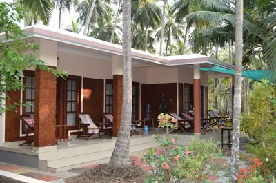 a house with palm trees in front of it at legacy beach stay kannur in Kannur