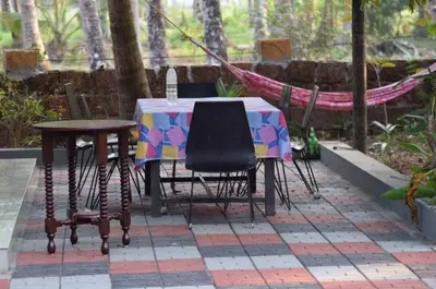 a table and chairs and a hammock on a patio at legacy beach stay kannur in Kannur