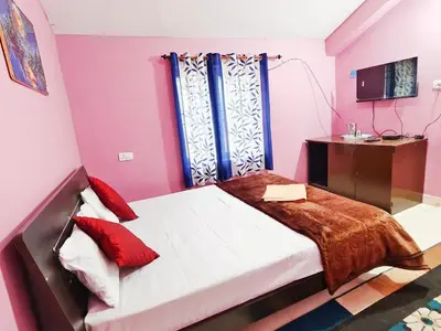 a bedroom with a bed with red pillows and a television at Greenland 2bed room hall villa in Ooty