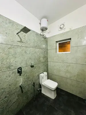 a bathroom with a toilet and a window on the wall at SURAAS Homestay Vythiri in Vythiri