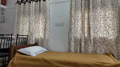 a bedroom with a bed and curtains and a table at Couples Nest in Kottakamboor
