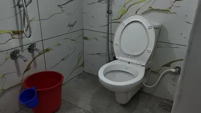 a bathroom with a toilet and a red bucket at Couples Nest in Kottakamboor
