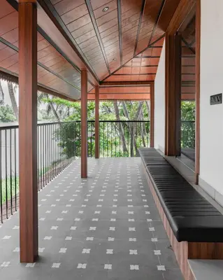 a pavilion with a wooden roof and black benches at Mayanadhi Resort in Irimbranallūr